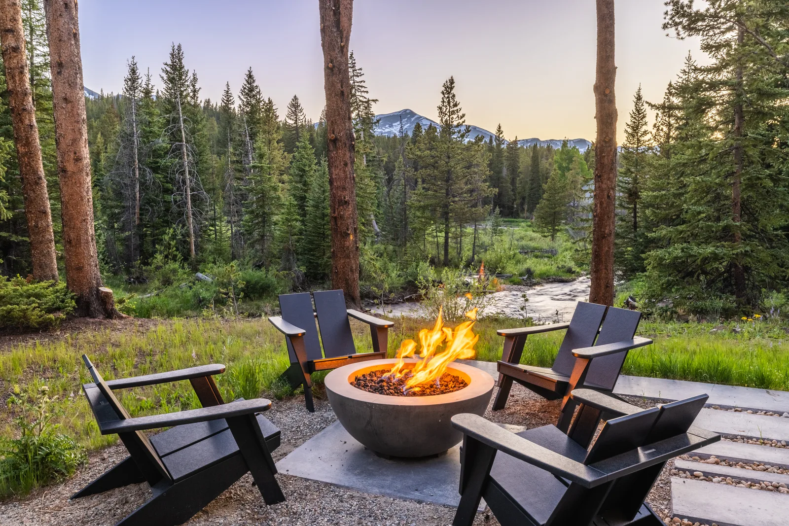 Fire pit seating beside a mountain creek at dusk