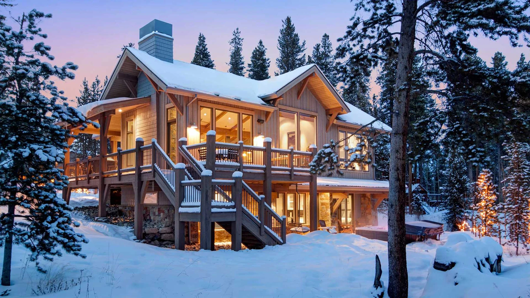 Warmly lit mountain home surrounded by snow-covered pine trees