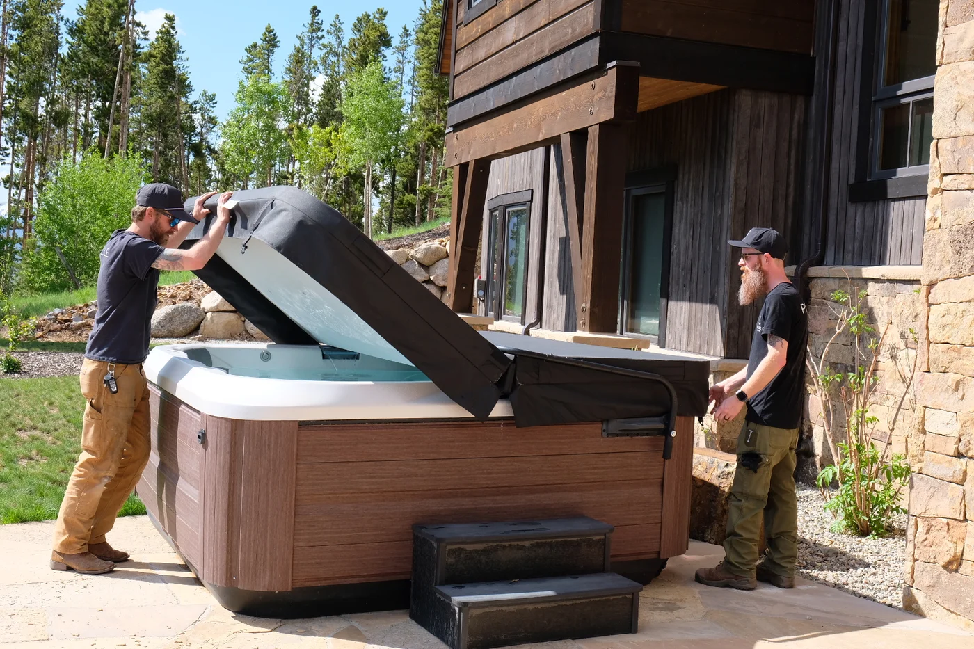 Team members lifting the cover of a mountain home's hot tub