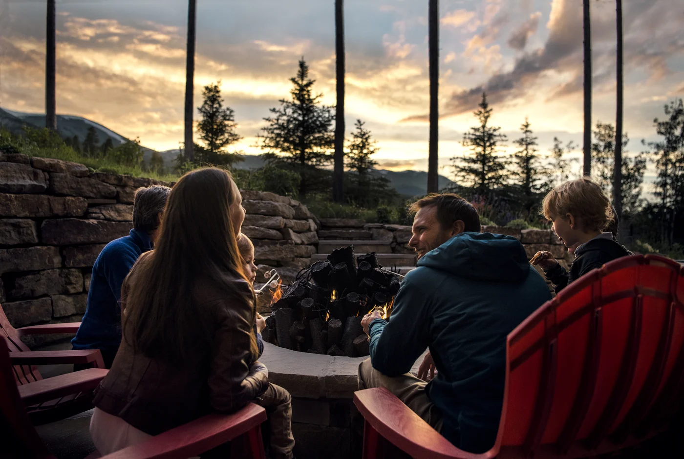 Guests enjoying a mountain home's outdoor fire pit at sunset