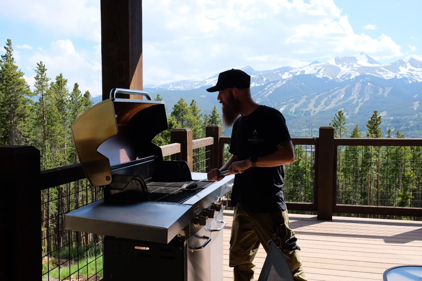 Pinnacle Lodging team member cleaning a grill on a mountain home's deck